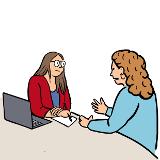 Zwei Frauen sitzen an einem Tisch. Die eine Frau spricht gerade. Sie sieht bekümmert aus. Die andere Frau hört ihr aufmerksam zu. Vor ihr ist ein Laptop und sie schreibt auf einem Papier mit. Zwei Frauen sitzen an einem Tisch. Die eine Frau spricht gerade. Sie sieht bekümmert aus. Die andere Frau hört ihr aufmerksam zu. Vor ihr ist ein Laptop und sie schreibt auf einem Papier mit.